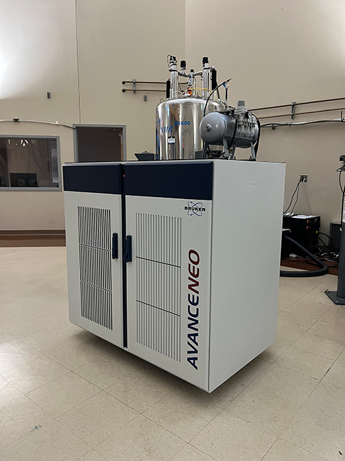 A Bruker AVANCE NEO NMR spectrometer stands in a laboratory setting with visible equipment and cables attached.